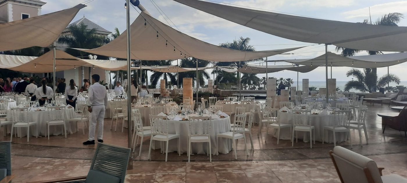 Cena de boda bajo velas de sombra blancas en una terraza al aire libre